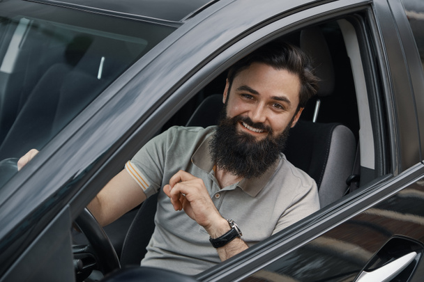 Молодий чоловік посміхається під час водіння автомобіля
 - Фото, зображення