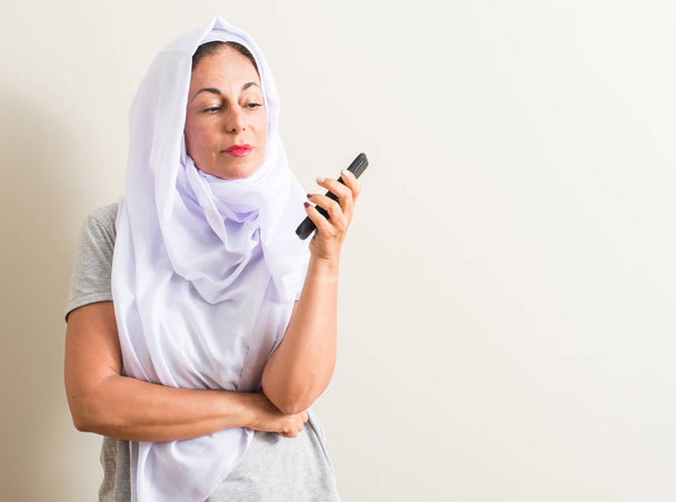 Mulher árabe usando smartphone rosto sério pensando em questão, ideia muito confusa
 - Foto, Imagem