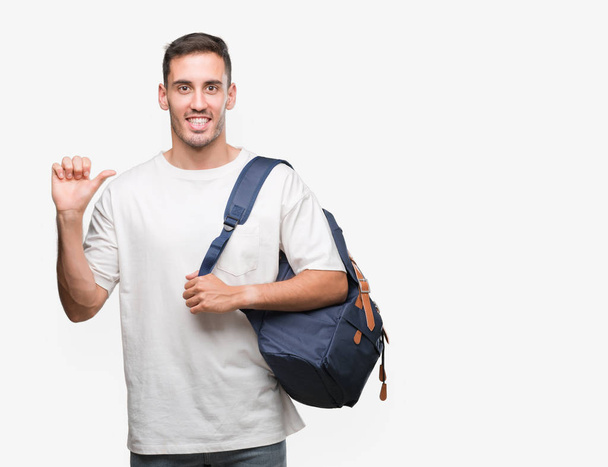Guapo joven sosteniendo la mochila señalando con la mano y el dedo hacia arriba con la cara feliz sonriendo
 - Foto, Imagen