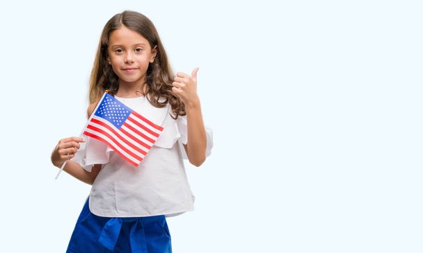 Brunette hispanic girl holding flag of United States of America happy with big smile doing ok sign, thumb up with fingers, excellent sign - Zdjęcie, obraz