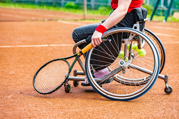 Jeune femme handicapée en fauteuil roulant jouant au tennis sur un court de tennis
. - Photo, image