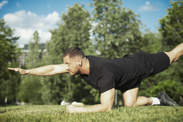 Young attractive man stretching outdoors in the park. - Foto, Imagen