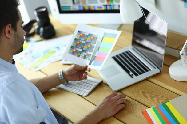 Retrato de jovem designer sentado no estúdio gráfico na frente de laptop e computador enquanto trabalhava online - Foto, Imagem