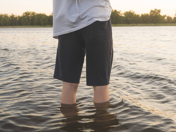 Закрыть юные ноги подростка стоя в морской воде
 - Фото, изображение