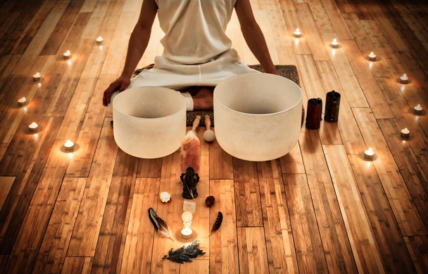 Homme assis en indien derrière ses deux bols de cristal musical, avec une exposition d'objet sacré et entouré de bougies
 - Photo, image