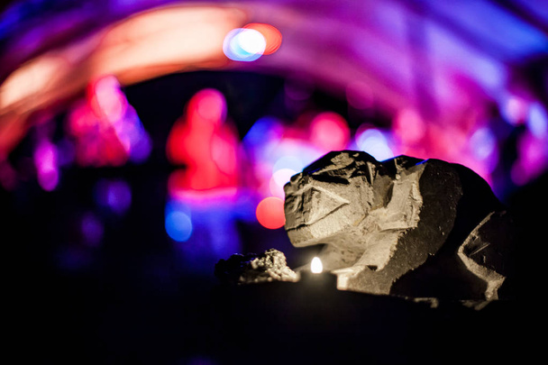 Gargoyle kivi veistos valaistu kynttilän valo, sumea violetti ja punainen tausta
 - Valokuva, kuva