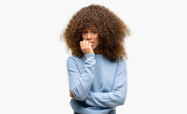 不安や、緊張を探しているセーターを着ているアフリカ系アメリカ人の女性は爪をかむ口の手します。不安の問題. - 写真・画像