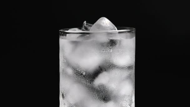 Üveg pohár jég és a víz a fekete háttér. - Felvétel, videó