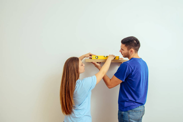 Young married couple install shlef on the wall - Fotó, kép