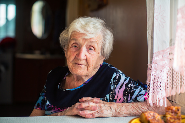Ritratto di una donna anziana seduta a tavola
. - Foto, immagini