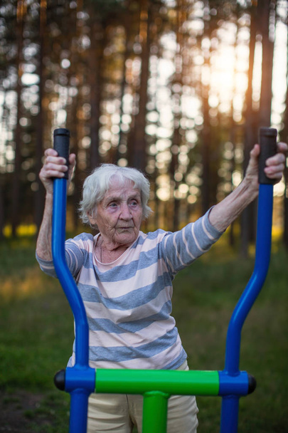 Mujer mayor haciendo ejercicio en el patio de recreo deportivo de la calle
. - Foto, imagen