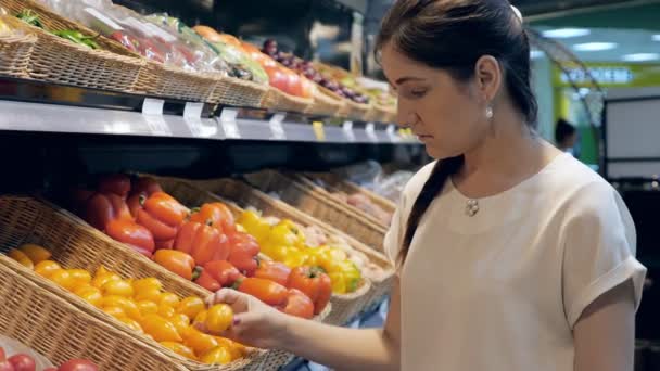 食料品店で若い女性が野菜を選択します。 - 映像、動画
