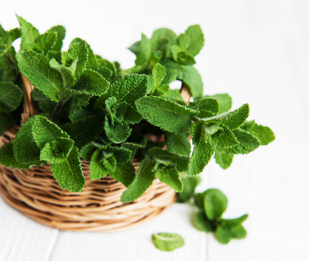 Basket with mint on a white wooden background - Photo, Image
