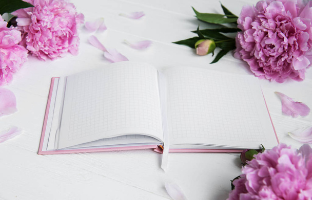 note book with peonies on a white wooden background - Foto, Imagen
