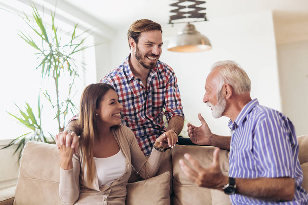 Young couple talking with their senior father at home - Foto, imagen