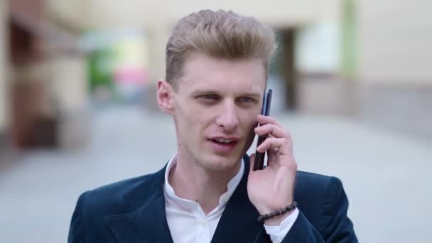 Young pensive businessman talking on the phone outdoors. - Filmagem, Vídeo