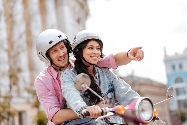Tour on motorbike. Low angle of merry optimistic couple wearing helmets and smiling - Photo, image