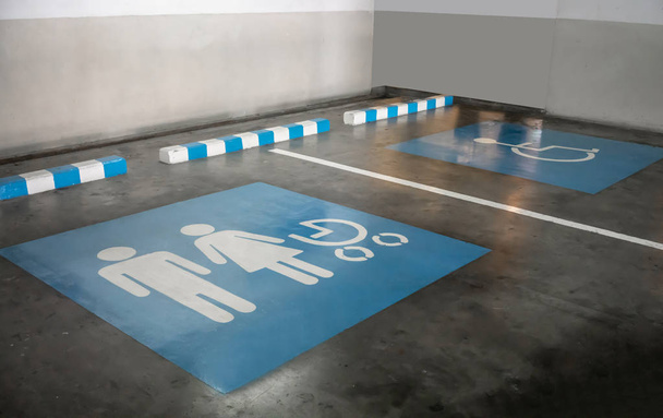 El cartel internacional para la familia y un puesto de estacionamiento para discapacitados en un estacionamiento. Señal de estacionamiento prioritaria
. - Foto, Imagen