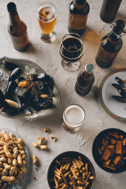 vista superior de aperitivos, mejillones con cubitos de hielo y cerveza fría dispuestos en la mesa de hormigón
 - Foto, Imagen
