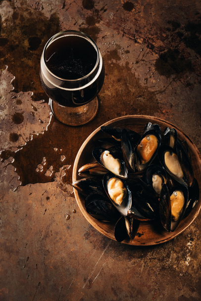 top view of glass of cold beer and mussels in bowl on rust surface - Photo, Image