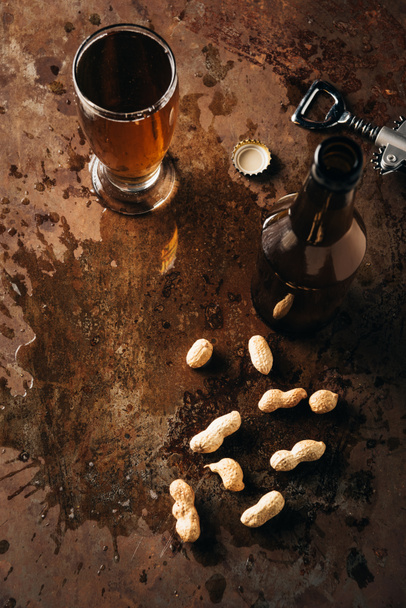 vista superior de cacahuetes, abridor de botellas y cerveza en la superficie oxidada
 - Foto, imagen