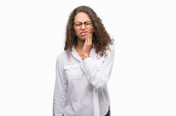 Beautiful young hispanic woman touching mouth with hand with painful expression because of toothache or dental illness on teeth. Dentist concept. - Foto, imagen