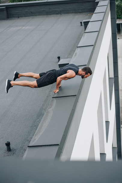 handsome sportsman training and standing on hands on roof  - Foto, Bild