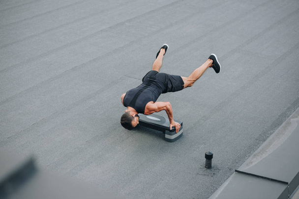 vista de ángulo alto del entrenamiento de deportista con plataforma escalonada y de pie sobre las manos en el techo
 - Foto, Imagen