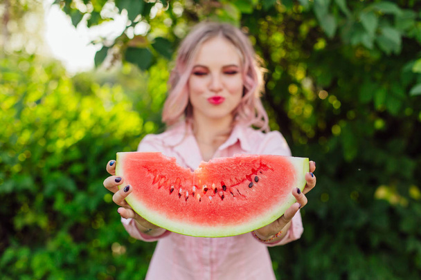 Beautiful smiling young woman with pink hair holding sweet juicy watermelon in hands - Zdjęcie, obraz