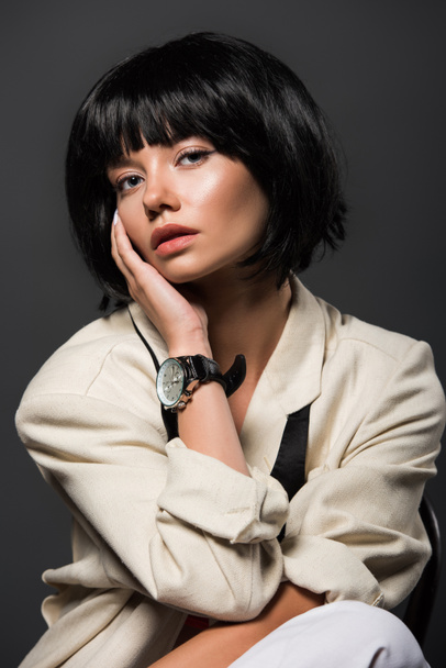 close-up portrait of young woman in stylish jacket with male wrist watch isolated on grey - Photo, Image