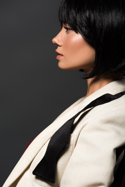 boční pohled atraktivní mladá žena v elegantní sako a nevázanou motýlek izolované Grey - Fotografie, Obrázek
