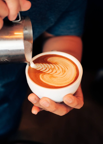 Close up barista hands pouring milk for make coffee latte art in coffee shop cafe. - 写真・画像