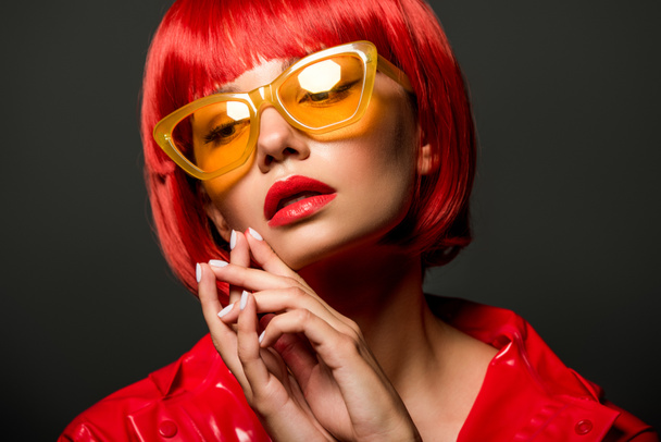 ritratto ravvicinato di giovane donna elegante in giacca di lattice rossa e occhiali da sole gialli vintage isolati su grigio
 - Foto, immagini