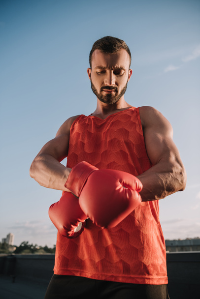 handsome sportsman tying boxing glove on roof - Zdjęcie, obraz