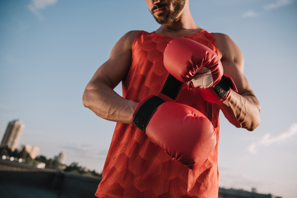 cropped image of sportsman tying red boxing glove on roof - Φωτογραφία, εικόνα