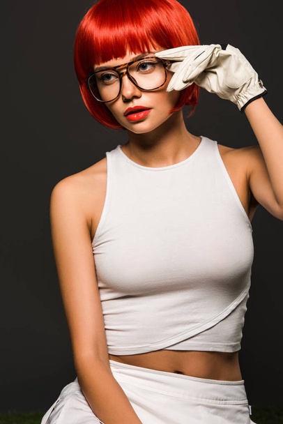 séduisante jeune femme avec bob rouge coupé en gant de golf et des lunettes élégantes regardant loin isolé sur gris
 - Photo, image