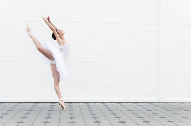 Vista lateral clásica bailarina de ballet. Hermosa bailarina elegante en posición de ballet de práctica de tutú blanco
. - Foto, Imagen
