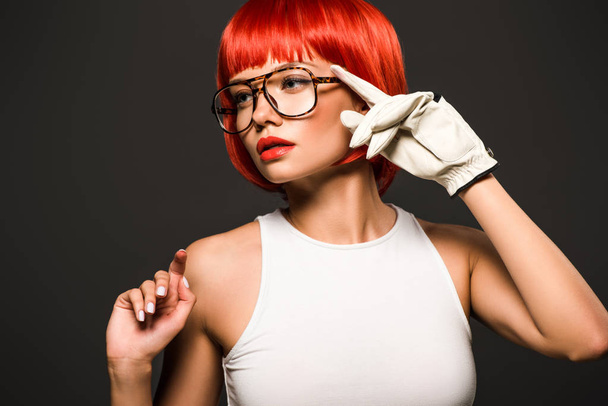 beautiful young woman with red bob cut in golf glove and stylish eyeglasses isolated on grey - Photo, Image