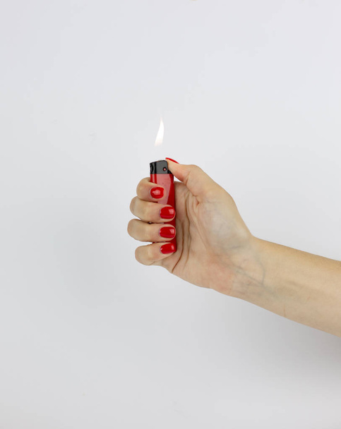 rotes Feuerzeug mit Feuer in Frauenhand isoliert auf weißem Hintergrund - Foto, Bild