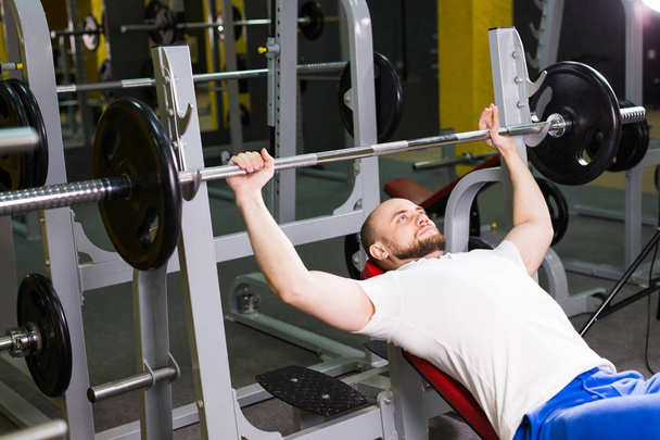 Sport, fitness, trening i koncepcja ludzie - muskularny mężczyzna robi ciężkich ćwiczeń, pompowania mięśni na wyciskaniu - Zdjęcie, obraz