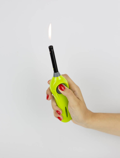 green multipurpose lighter with fire in womans hand isolated on white background - Photo, image