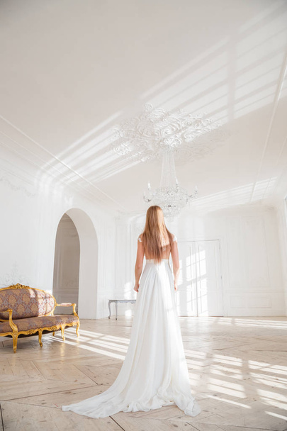 Prise de vue de mode de belle femme blonde en robe blanche debout sur fond blanc intérieur
 - Photo, image