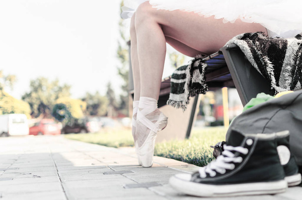 Image recadrée d'une jeune ballerine assise sur un banc, à l'extérieur
. - Photo, image