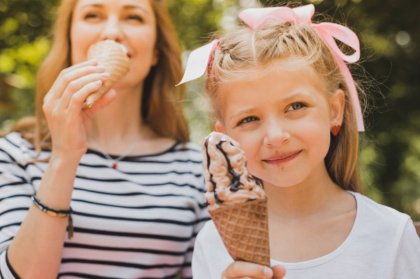 Blonde-haired daughter with cute hair style eating ice cream - Photo, Image