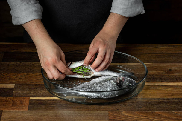 Chef cooking sea fish with seasoning on wooden table - Foto, Imagem