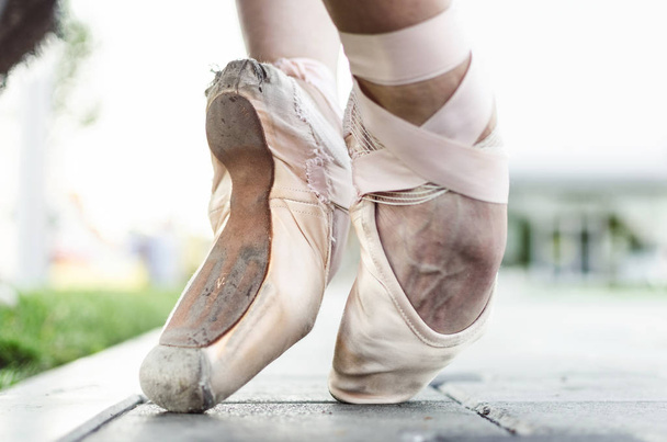 Close up of feet of young female classic ballet dancer in pointe shoes, posing in nature. - Foto, Imagen