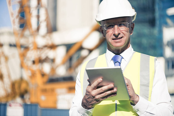 Senior engineer man in suit and helmet working on tablet pc - Фото, изображение