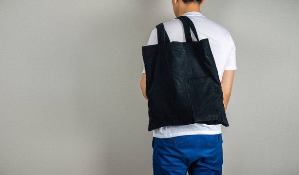 Man hanging black tote bag in the back - Photo, Image