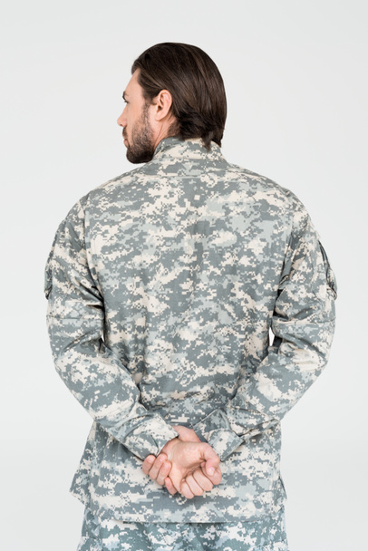 back view of male soldier in camouflage clothing isolated on grey - Photo, image
