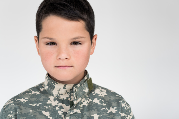 retrato de niño en uniforme militar mirando a la cámara sobre fondo gris
 - Foto, Imagen